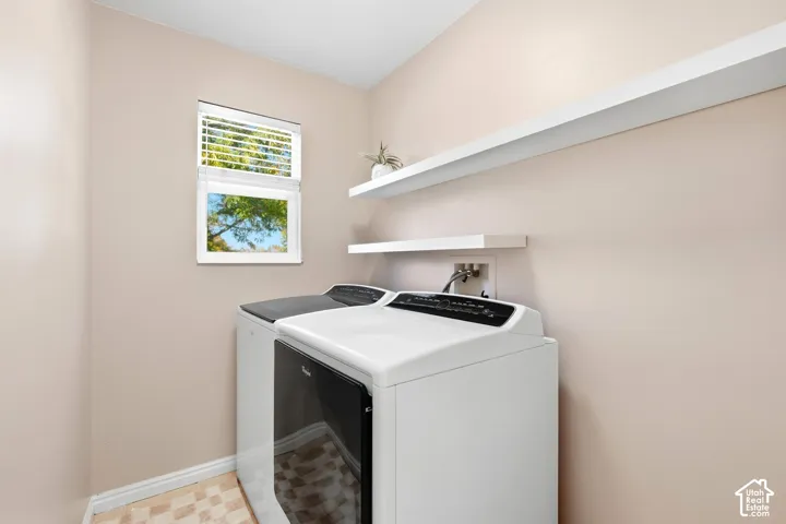 Window with blinds, two floating shelves, and tile flooring