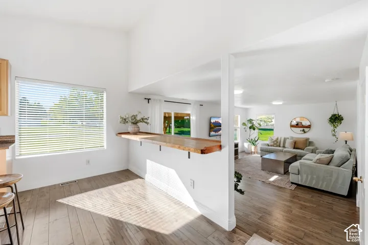 Open concept living space with wood-finish flooring, vaulted ceiling, and ample natural light