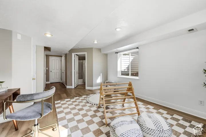 Recessed lighting, wood-finish flooring, white trim, and a window with a white frame