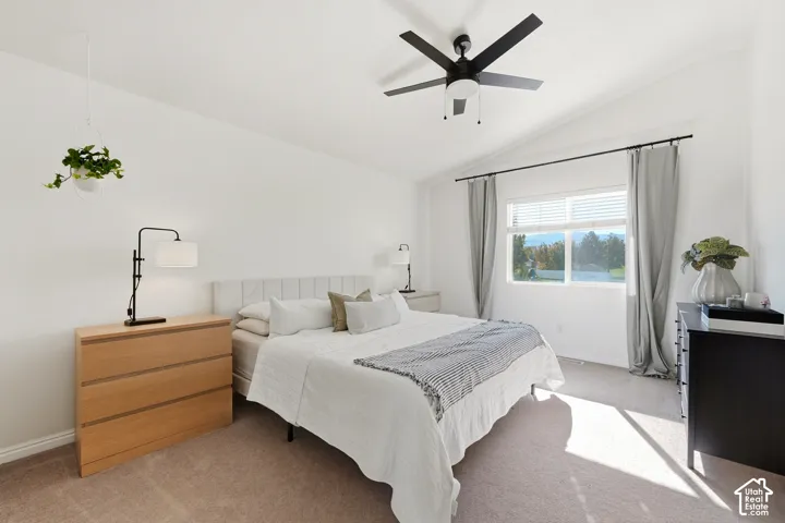 Vaulted ceiling featuring a ceiling fan, carpeted flooring, and a large window with blinds and curtains