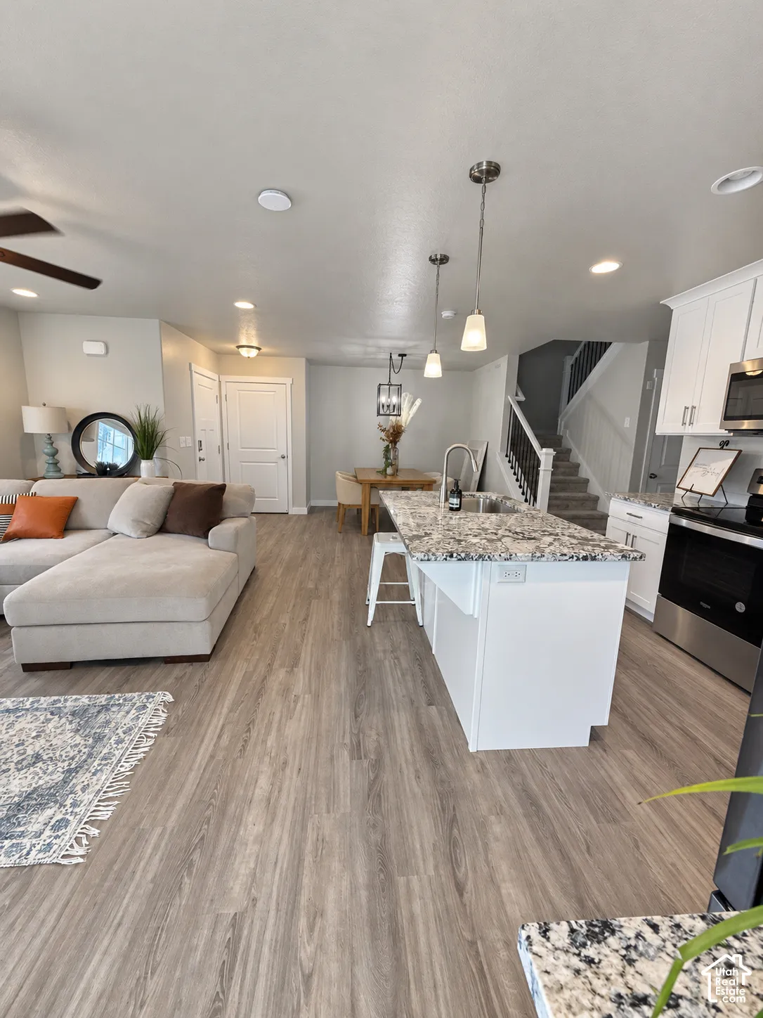 Kitchen featuring white cabinetry, stone-finish countertops, stainless steel appliances, and wood-finish flooring throughout