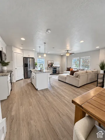 Open floor plan featuring wood-finish flooring, kitchen island with stone-surface countertop, recessed lighting, and stainless steel appliances