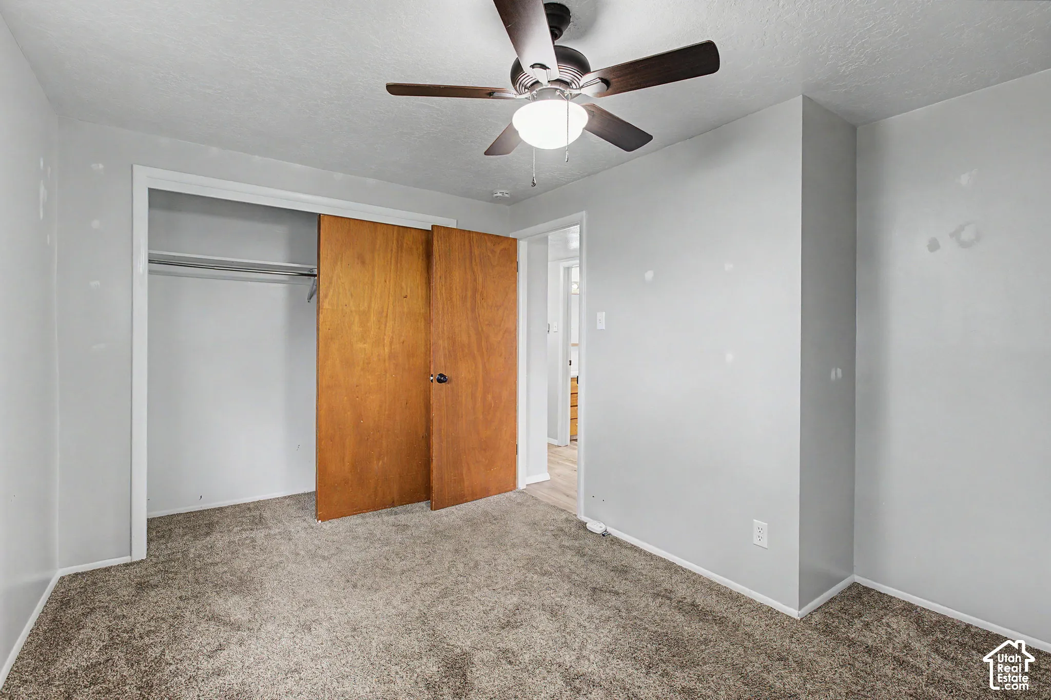 Carpeted flooring, ceiling fan with integrated lighting, wood-finish closet doors, and white trim throughout
