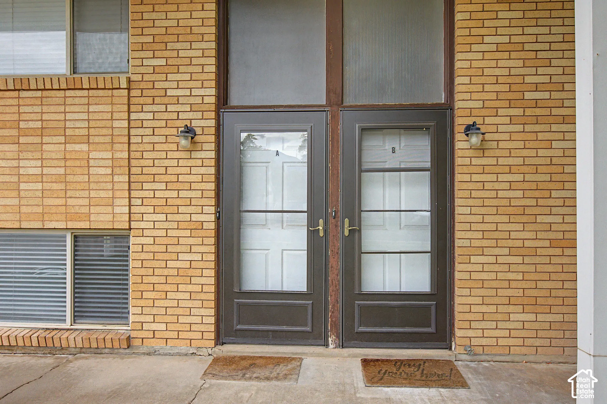 Brown brick exterior with a dual entry, transom window, and exterior wall sconces