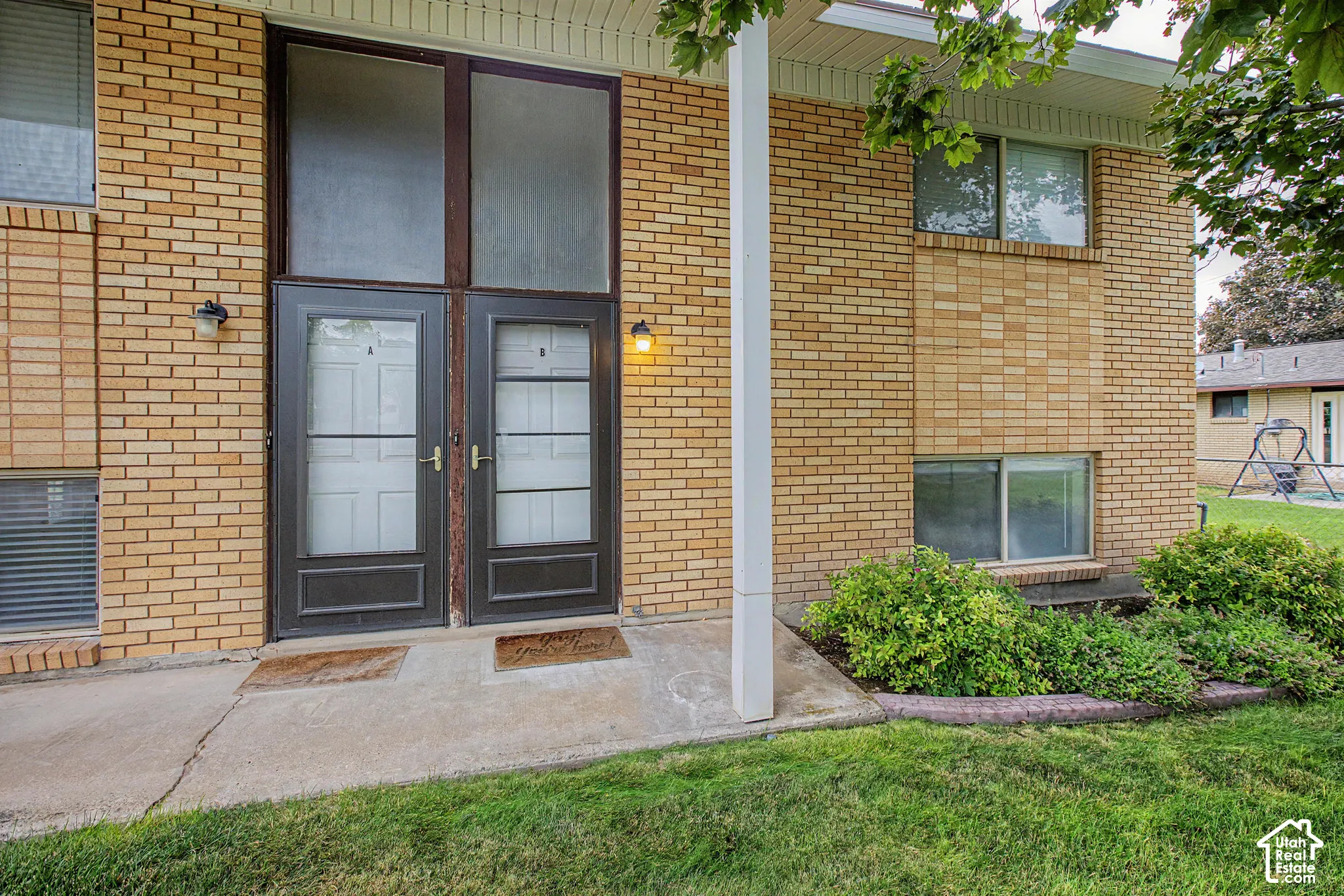 Brick exterior featuring double entry doors, transom windows, and exterior lighting fixtures