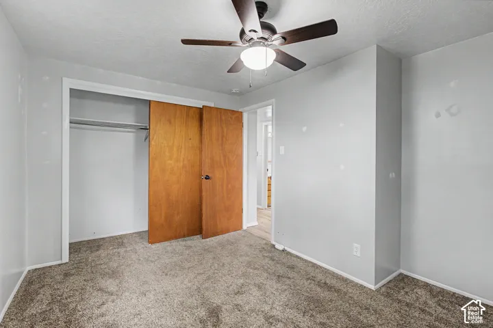 Carpeted flooring, ceiling fan with integrated lighting, wood-finish closet doors, and white trim throughout