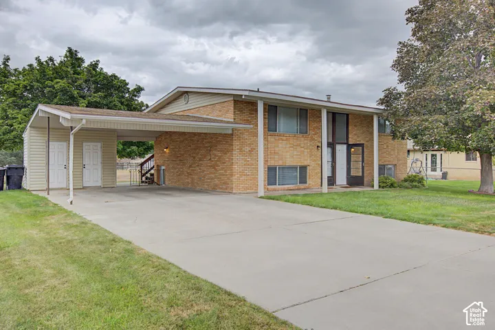 Brick exterior with a covered carport, concrete driveway, and covered entry