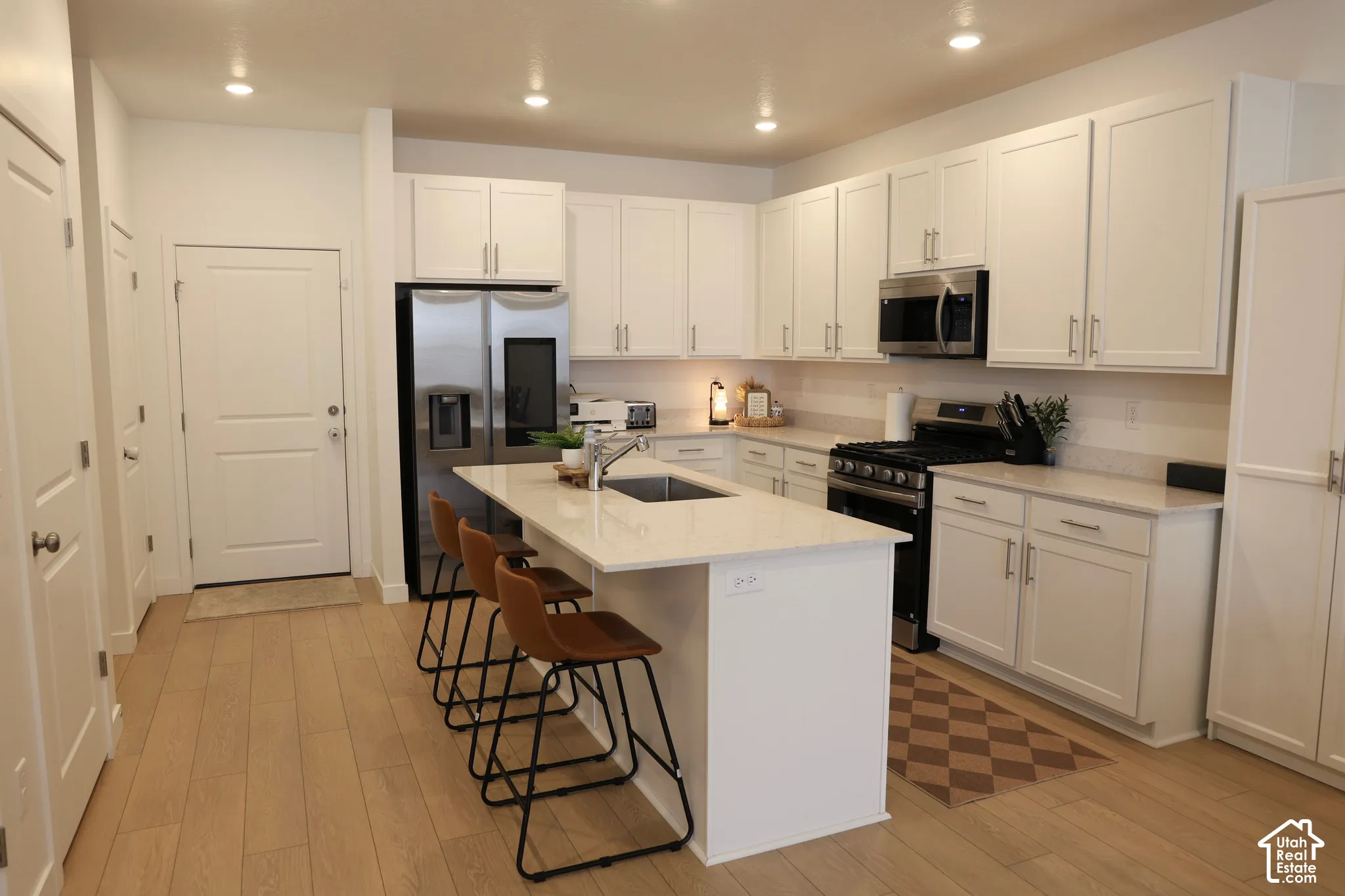 Contemporary kitchen featuring white cabinetry, light countertops, wood-finish flooring, and recessed lighting