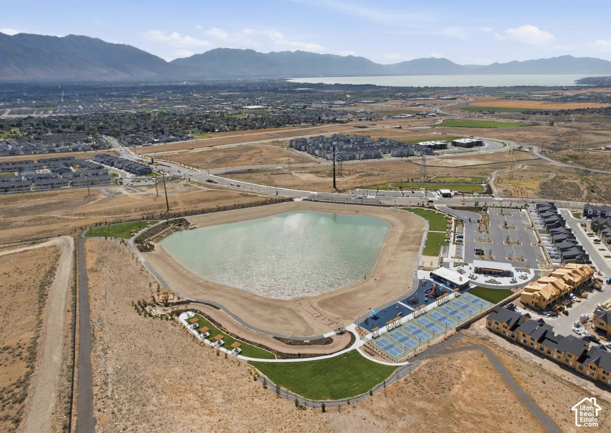 Aerial perspective showcasing a large body of water, tennis courts, and surrounding residential structures