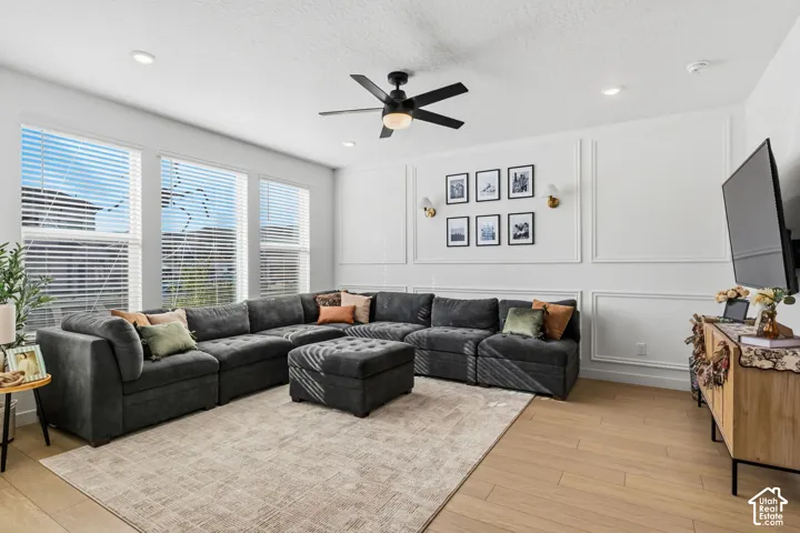 Recessed lighting, wood-finish flooring, multiple windows, a ceiling fan, and decorative wall molding