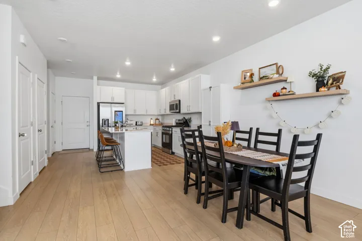 Open-concept living area with wood-finish flooring, white cabinetry, a kitchen island, and recessed lighting