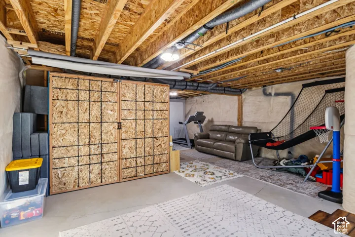 Unfinished basement with exposed ceiling joists and concrete flooring