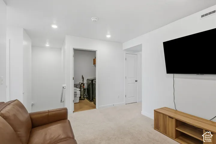 Recessed lighting, wall-mounted television, neutral carpeting, and white interior doors