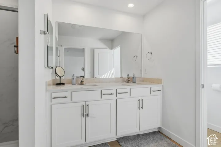 Dual vanity with white cabinetry and brushed nickel hardware, light-toned countertop, and an expansive wall-mounted mirror