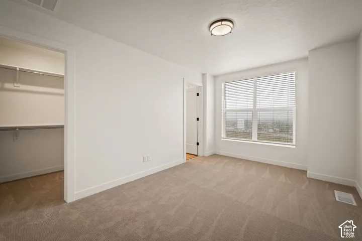 Carpeted room with a large window, horizontal blinds, and a flush-mount ceiling light