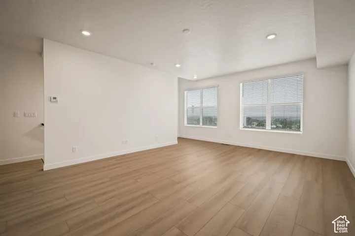 Recessed lighting, wood-finish flooring, and white walls