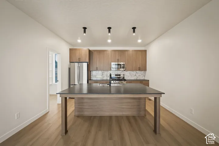 Modern kitchen featuring wood-finish cabinetry and a large island with a dark countertop