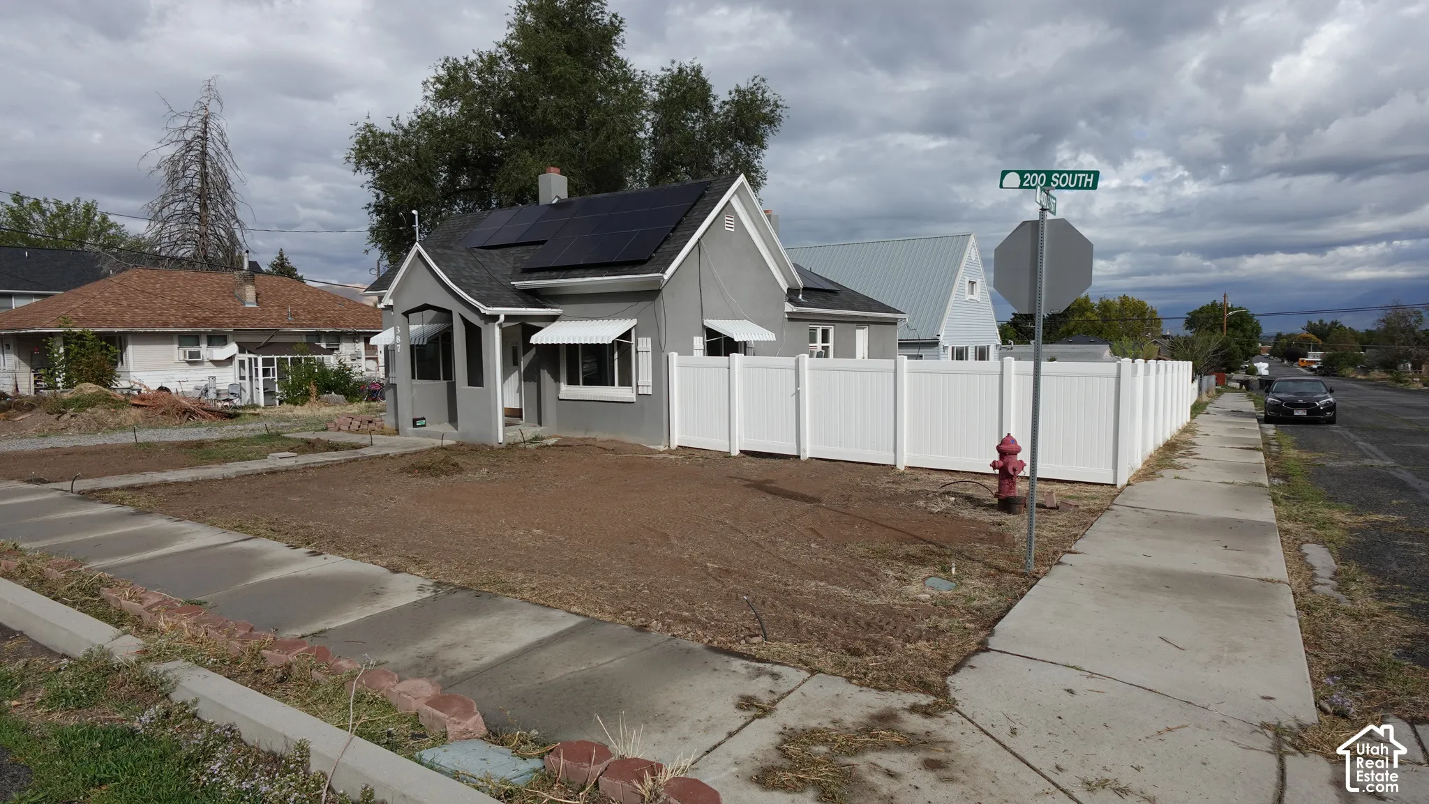 Gray exterior siding with white trim, a black shingle roof, and solar panels