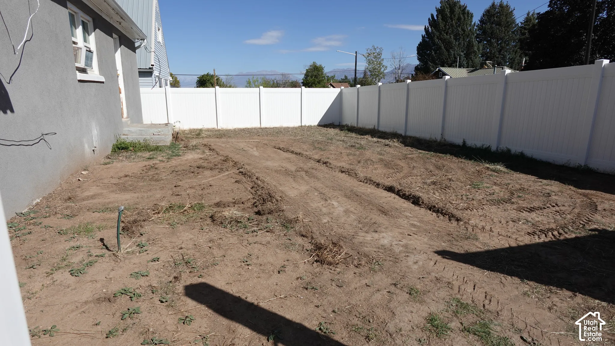 Expansive rear yard space featuring a full perimeter privacy fence and a leveled earth surface