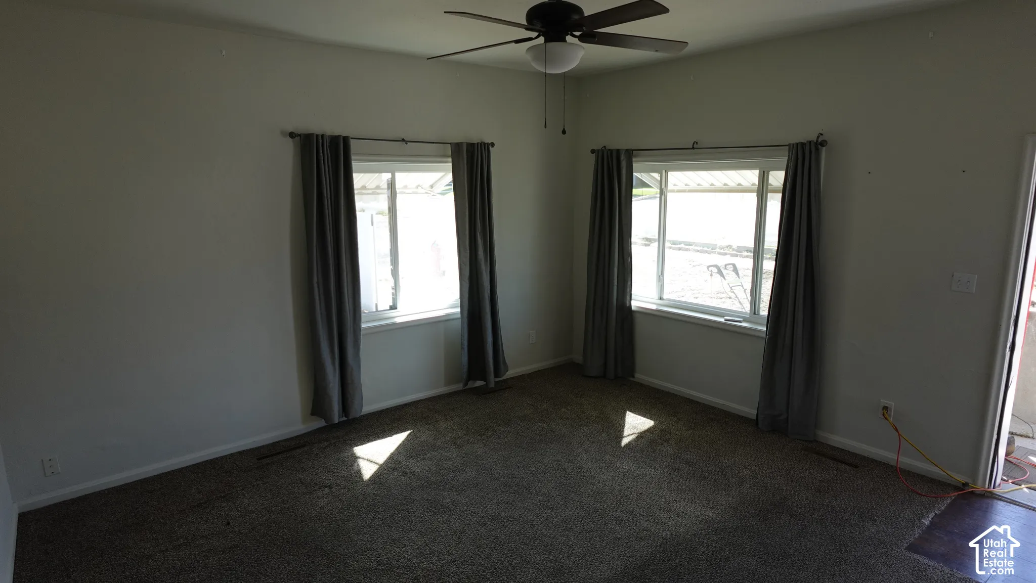 Room featuring two windows, a ceiling fan, and carpet flooring