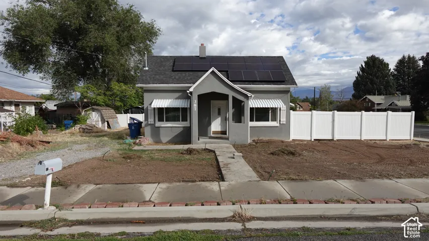 Charming single-story residence featuring a classic white exterior with dark roofing, front-facing covered entry, and multiple windows providing natural light