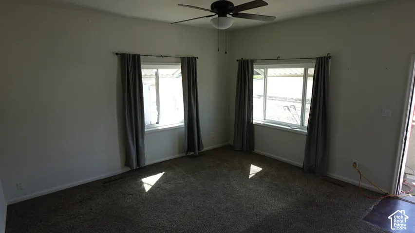 Room featuring two windows, a ceiling fan, and carpet flooring