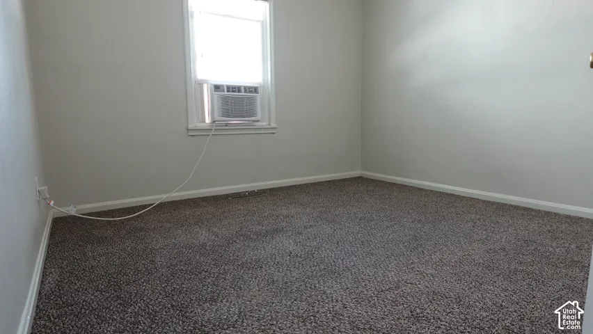 Spacious bedroom featuring neutral wall finishes, carpet flooring, and abundant natural light from a large window