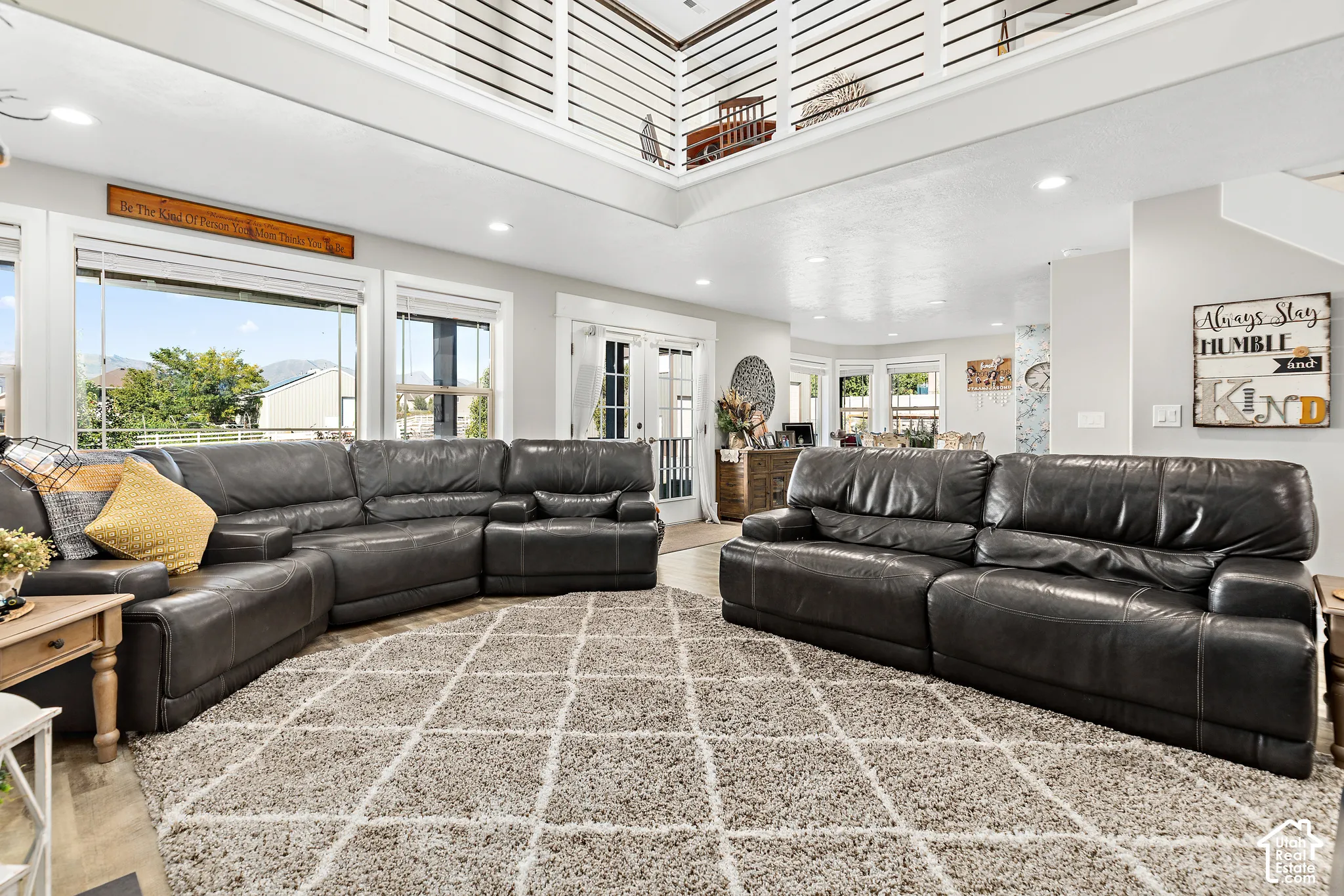 Vaulted ceiling with an open mezzanine, abundant natural light, recessed lighting, and wood-finish flooring