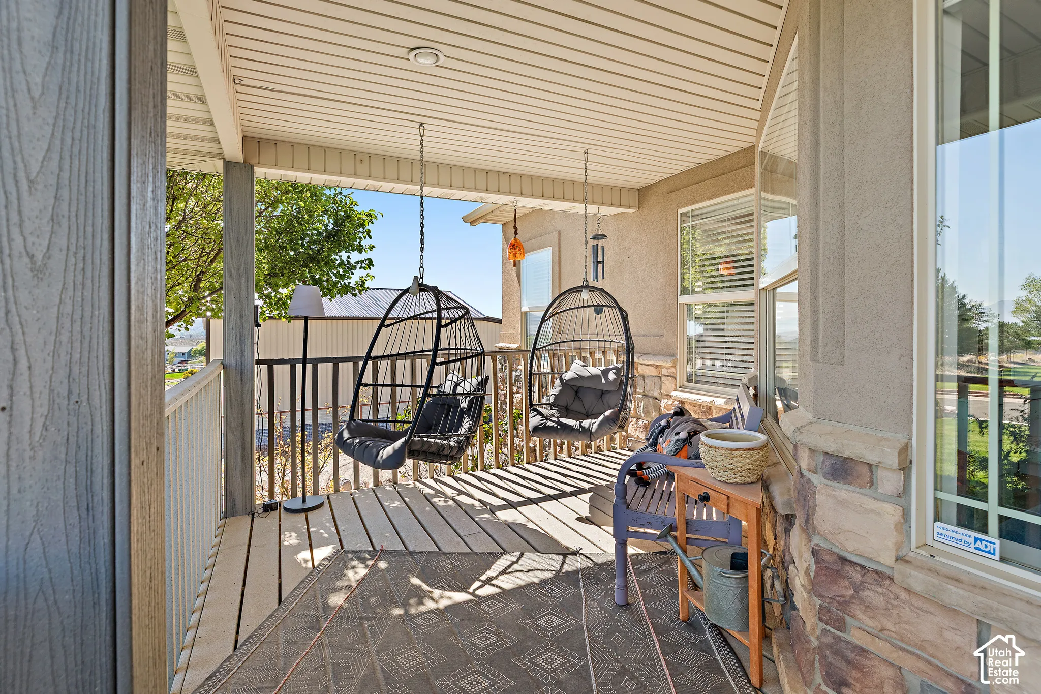 Covered outdoor patio with a planked ceiling, wood-finish flooring, and a stone-clad wall accent