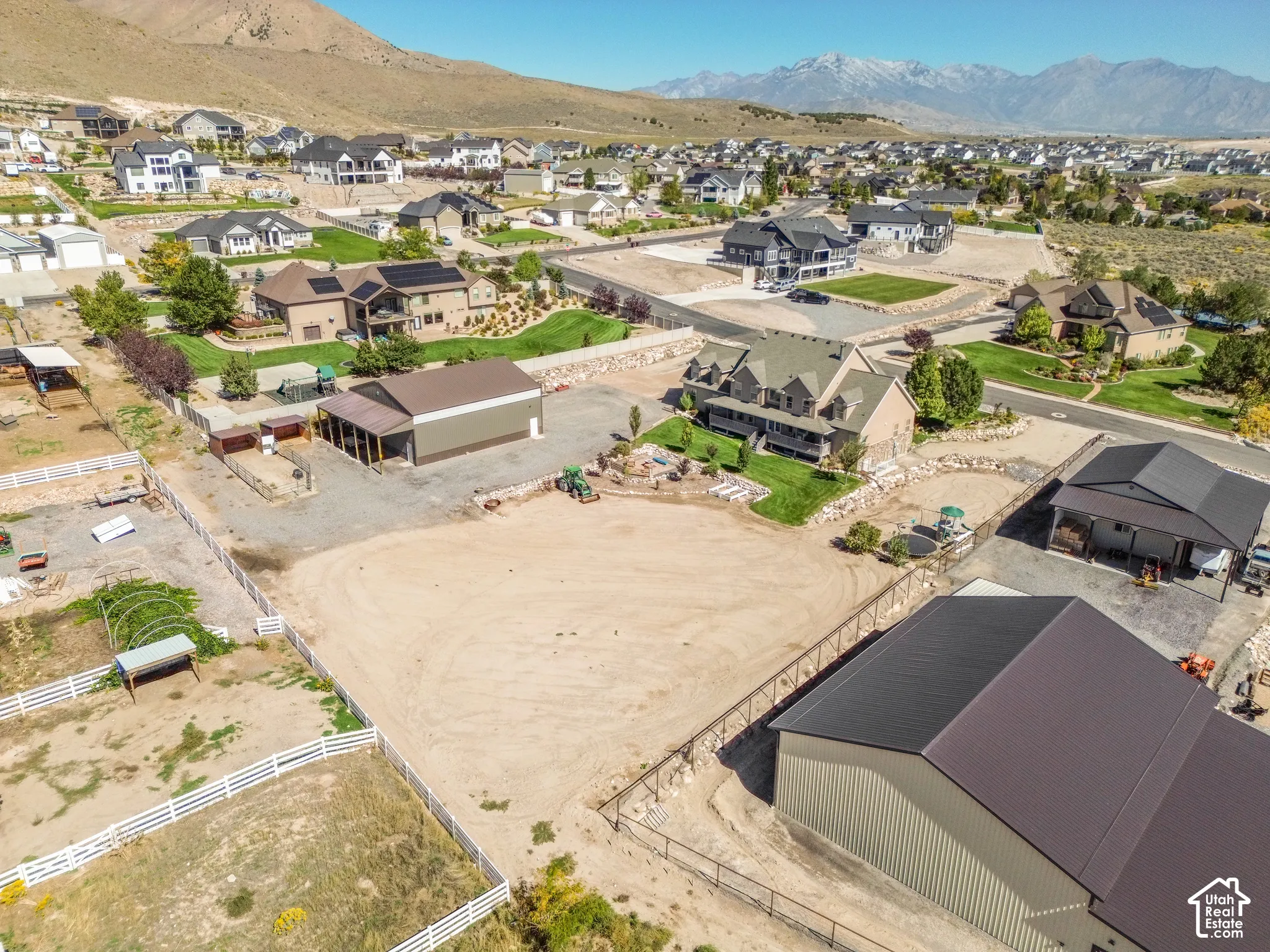 Expansive lot featuring a large outbuilding with a metal roof, an additional barn structure with a covered porch, and a fenced perimeter