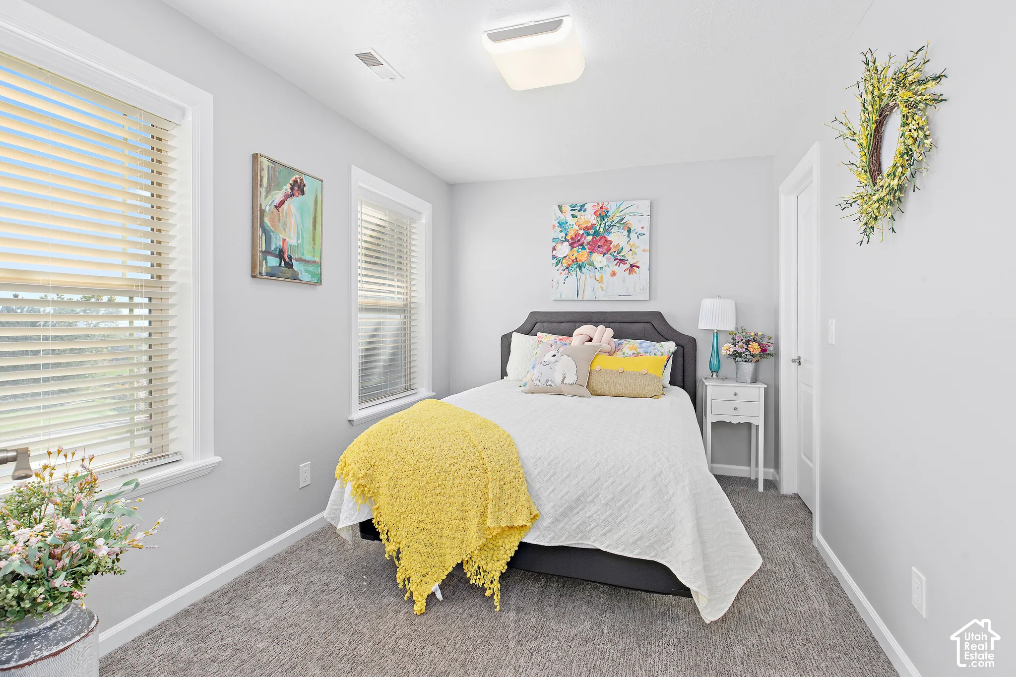 Light gray wall paint, two windows with blinds, white trim, gray carpet flooring, and a flush mount ceiling light