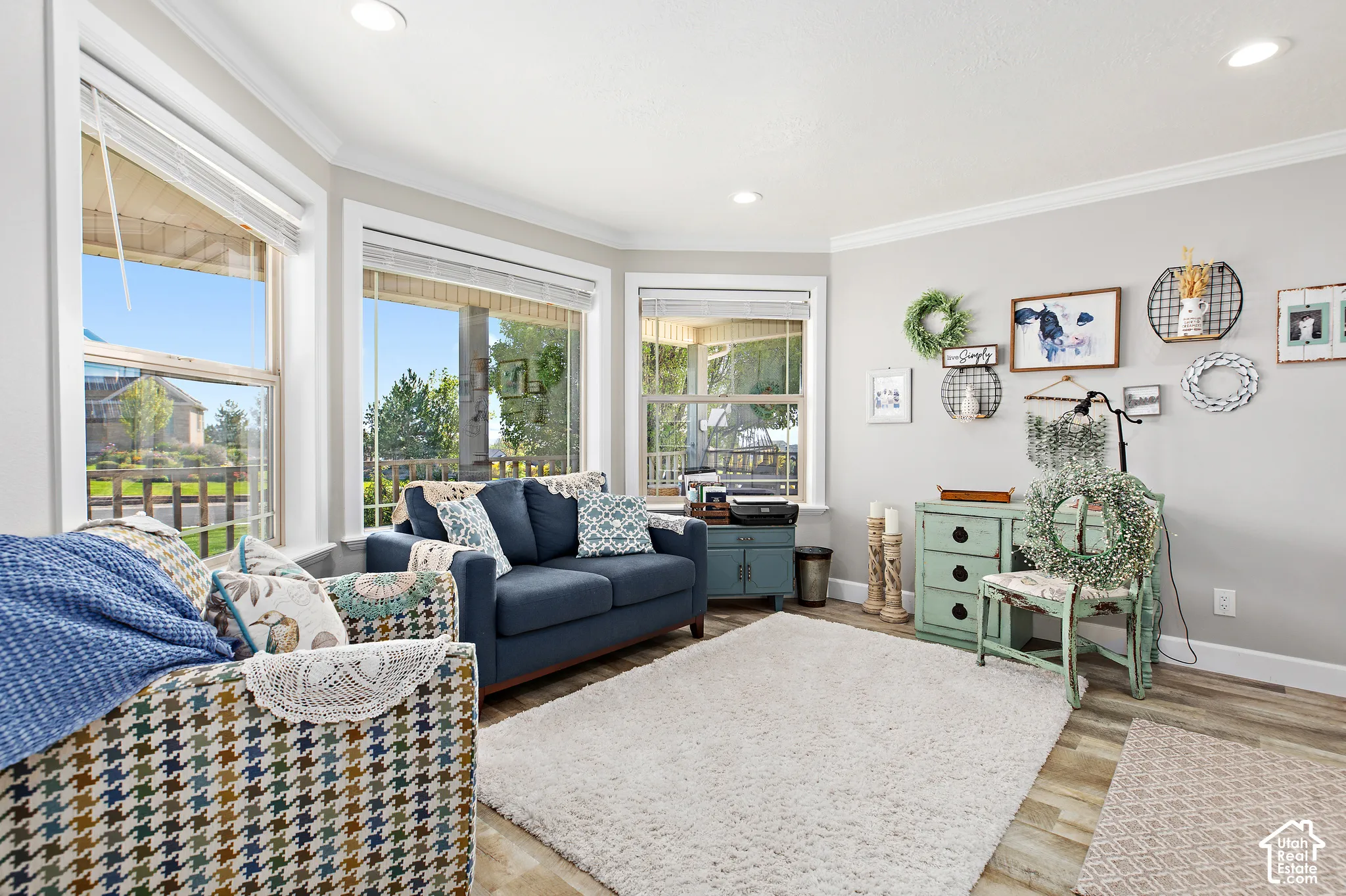 Bay window with multiple large windows, recessed ceiling lighting, crown molding, light wood-finish flooring, and light gray wall paint
