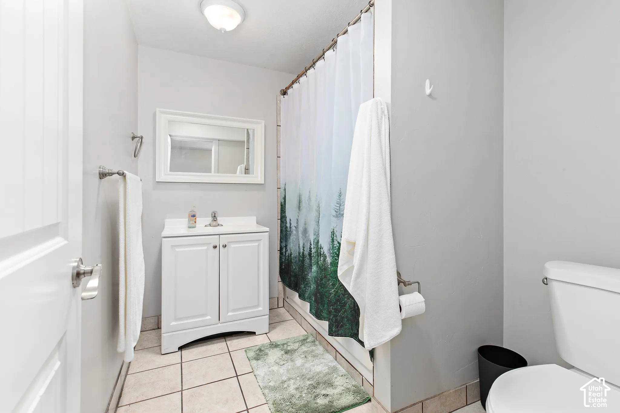 White vanity with under-sink storage, framed mirror, and tile flooring