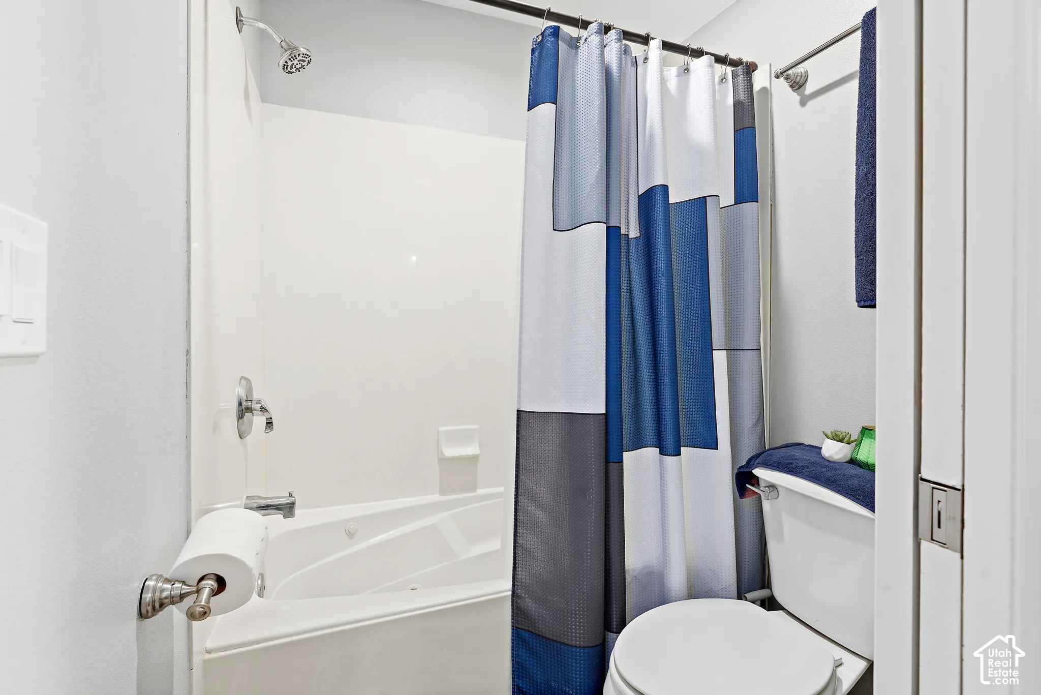 White full bathroom featuring a built-in bathtub with shower, chrome fixtures, and white walls