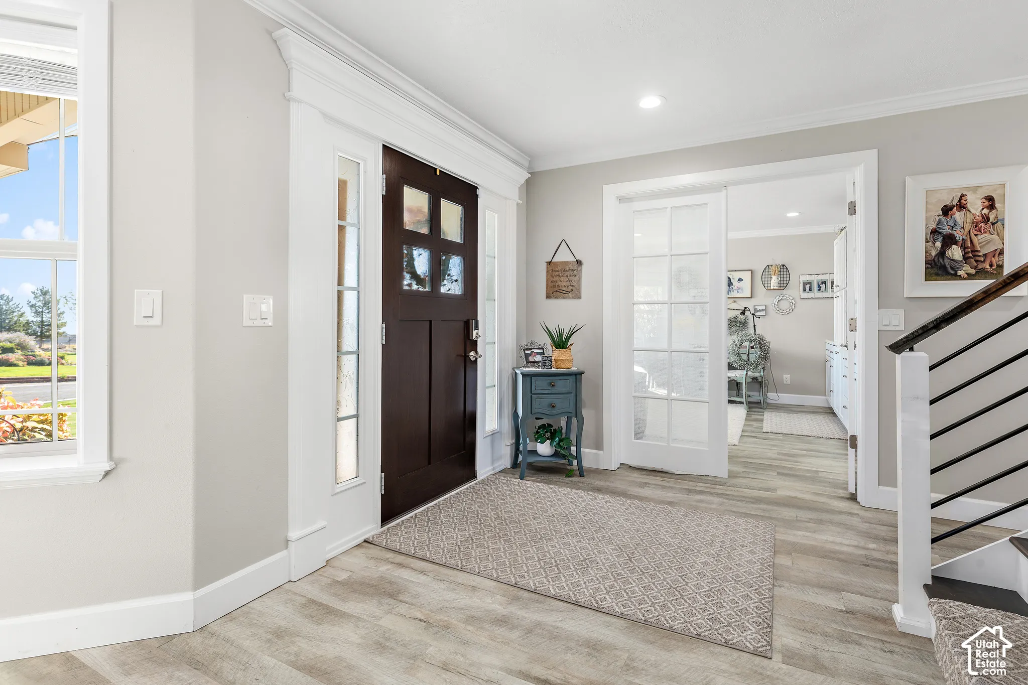 Entry area featuring wood-finish flooring, a dark wood entry door with glass panels, and a window with white trim