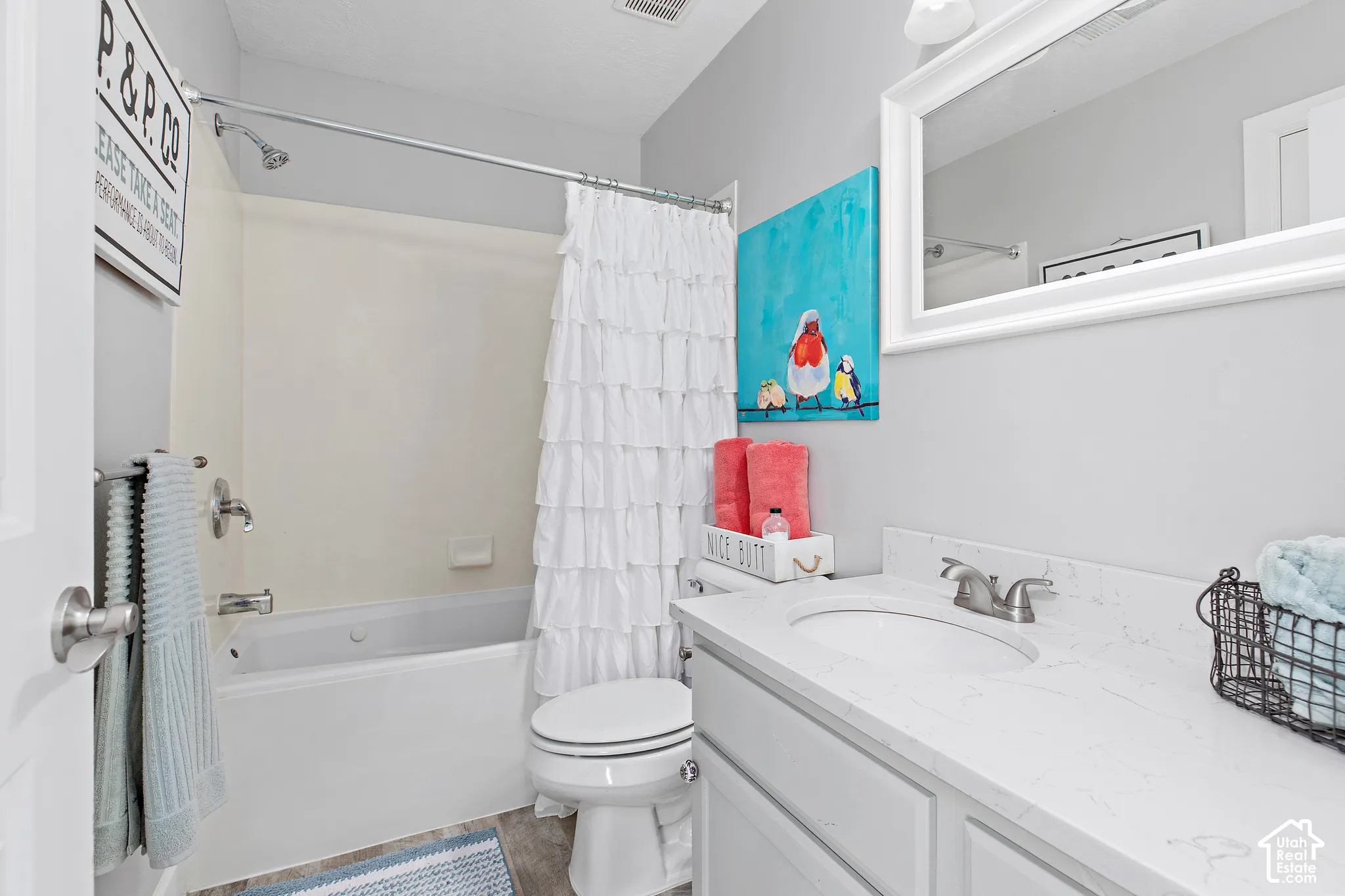 Bathroom featuring a white vanity with an undermount sink, a large framed mirror, and a full bathtub with an integrated shower