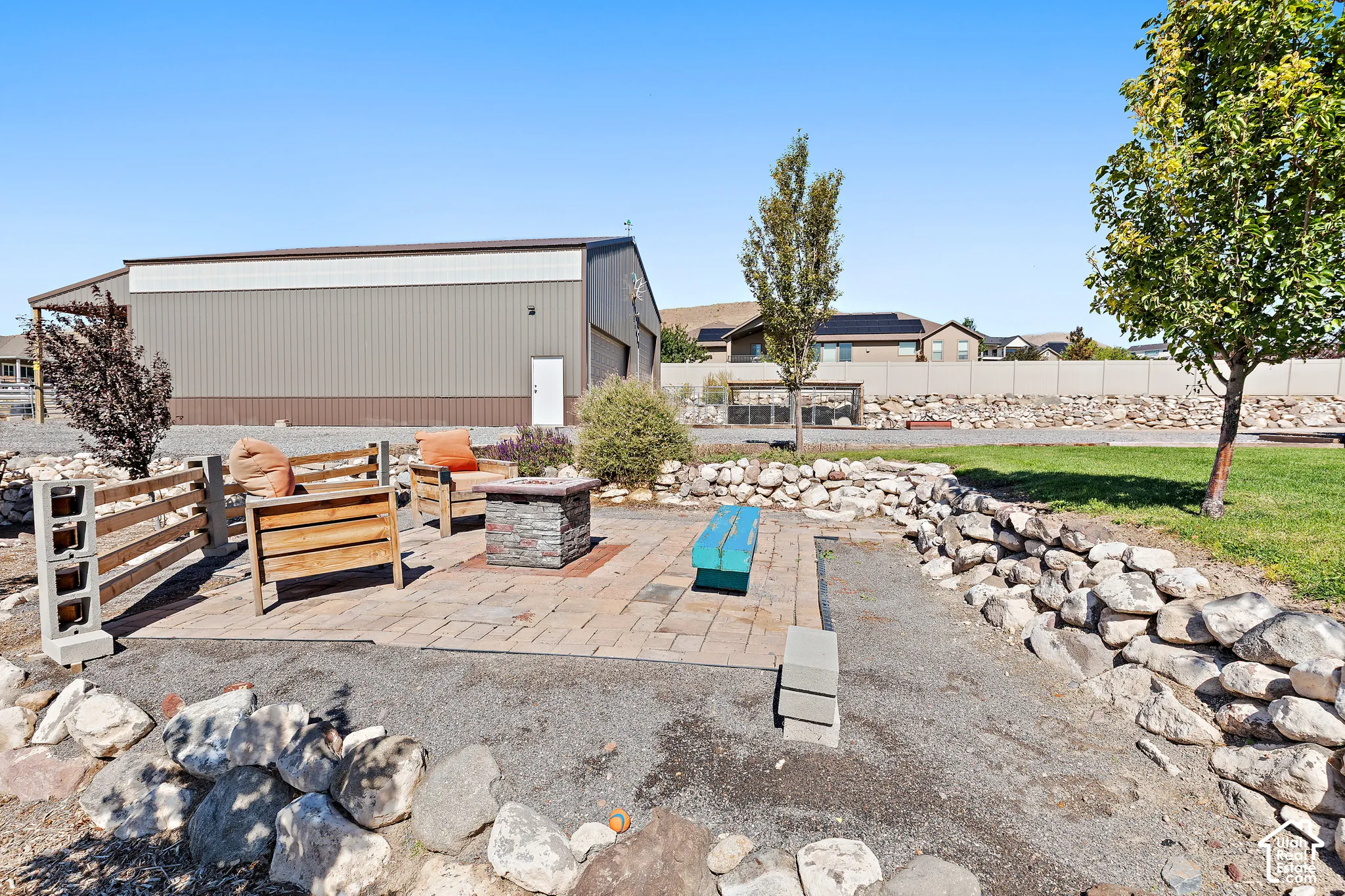 Expansive outdoor patio with paver flooring and a stone-clad fire pit