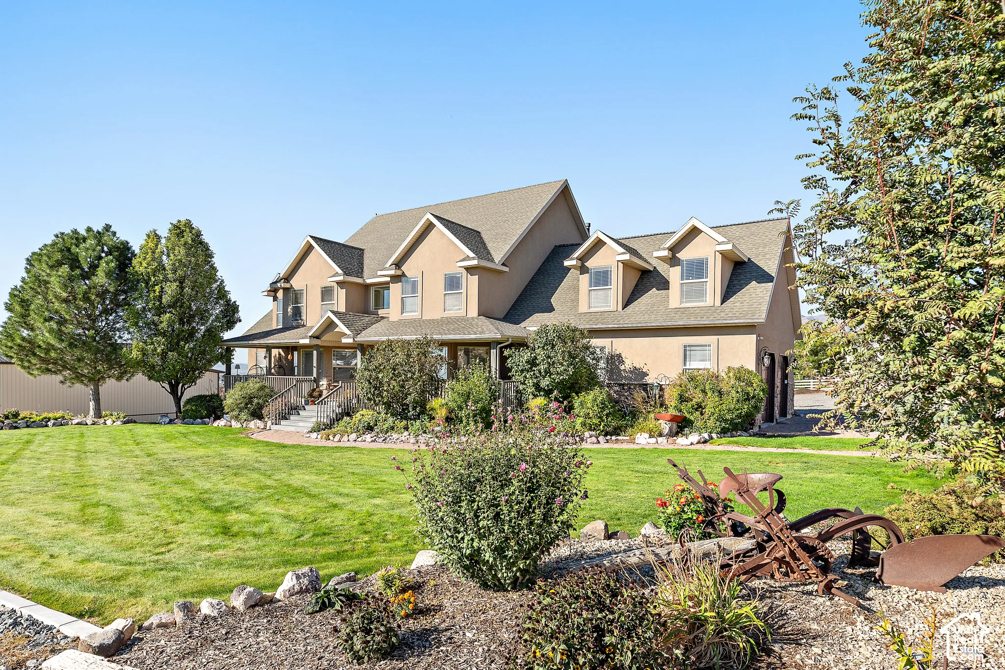 Stucco exterior residence featuring a covered front porch, dormer windows, and a multi-level roofline