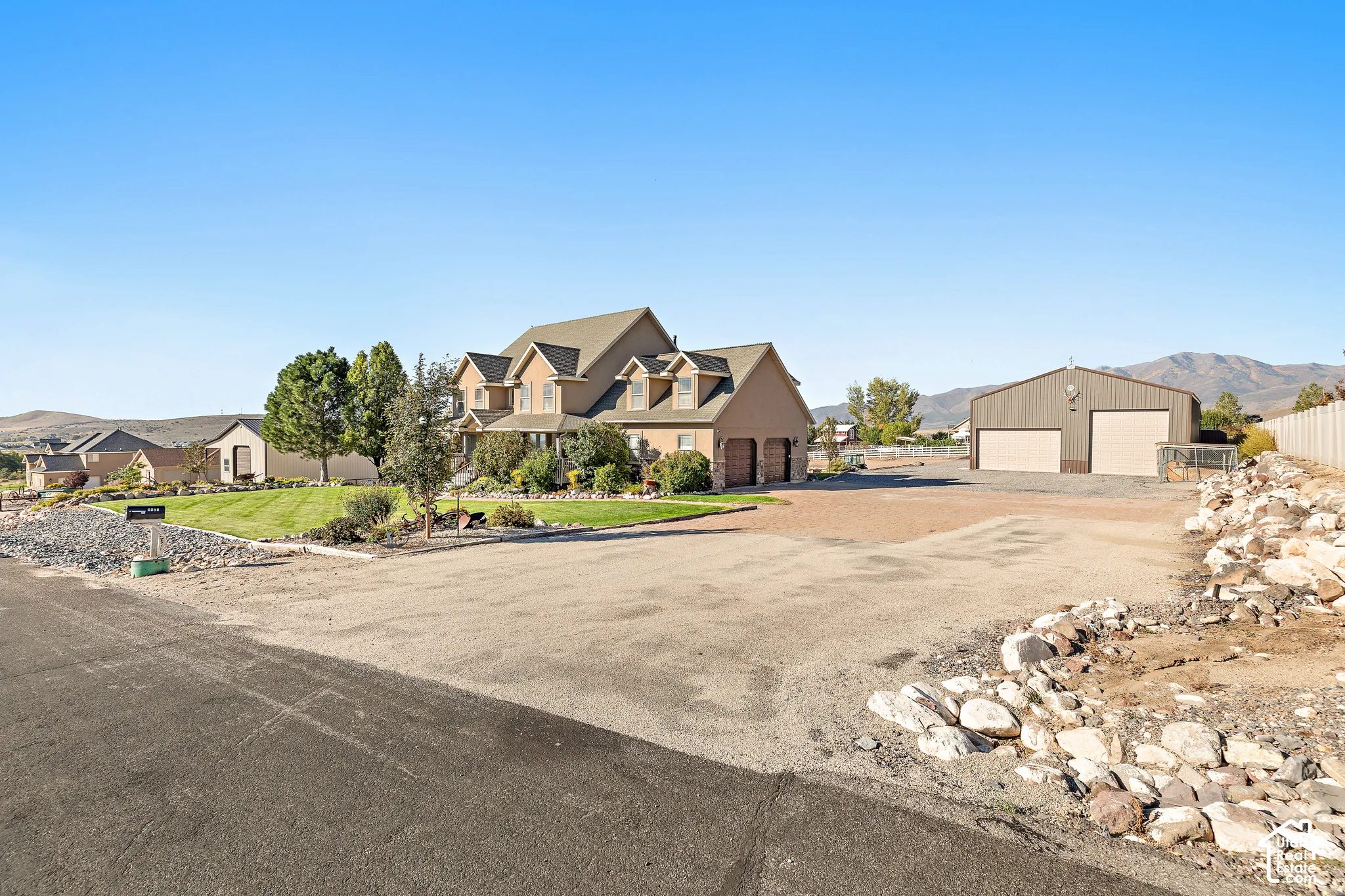 Two-story residence with a three-car garage, an additional detached two-car garage, and a expansive gravel lot