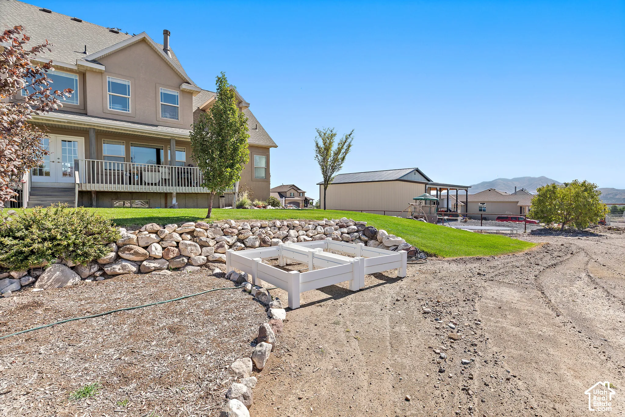 Two-story property with a light-colored stucco exterior, multi-pane windows, and a covered deck