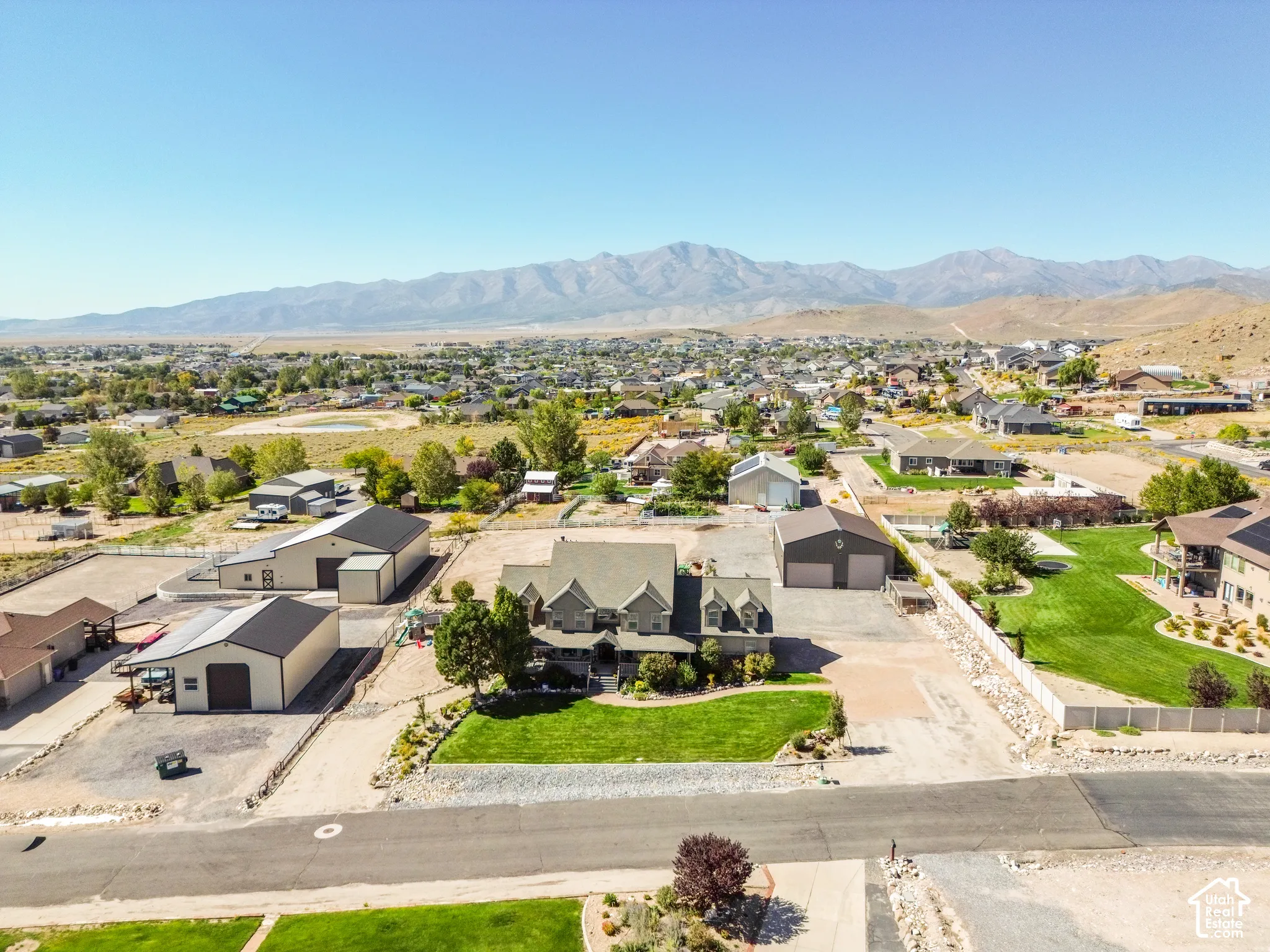 Expansive property featuring a multi-level residence, multiple detached outbuildings, and a large manicured front lawn