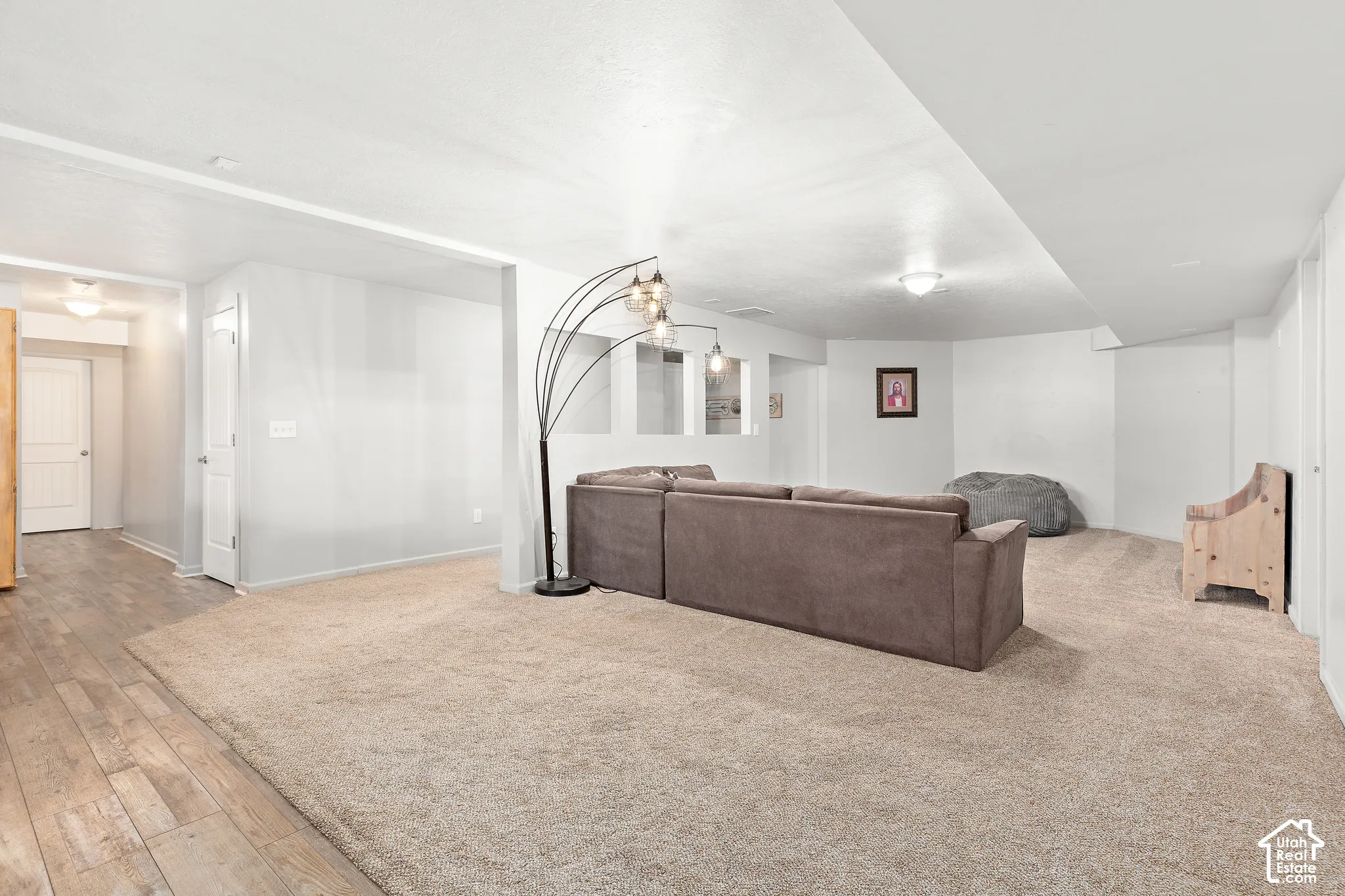 Expansive carpeted area with recessed lighting, light gray walls, and wood-finish flooring