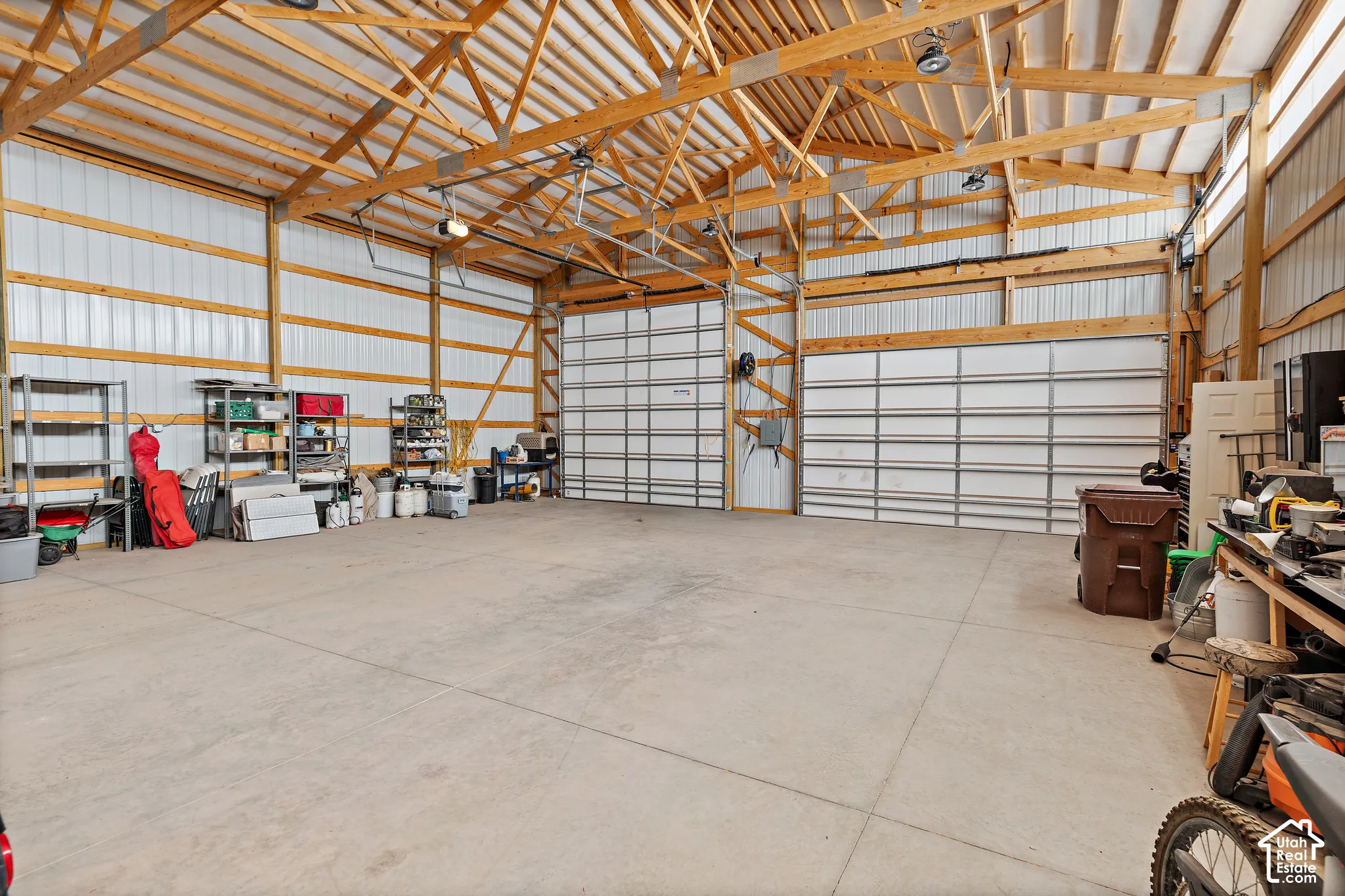 Spacious interior with exposed wood beam ceiling, concrete flooring, and multiple roll-up garage doors