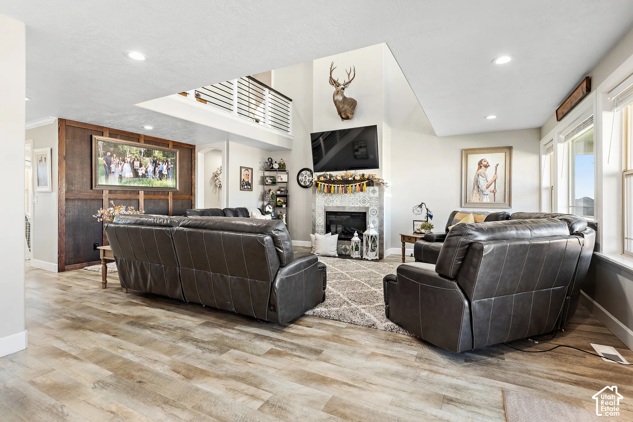 Wood-finish flooring, recessed lighting, and a prominent fireplace with decorative tile surround
