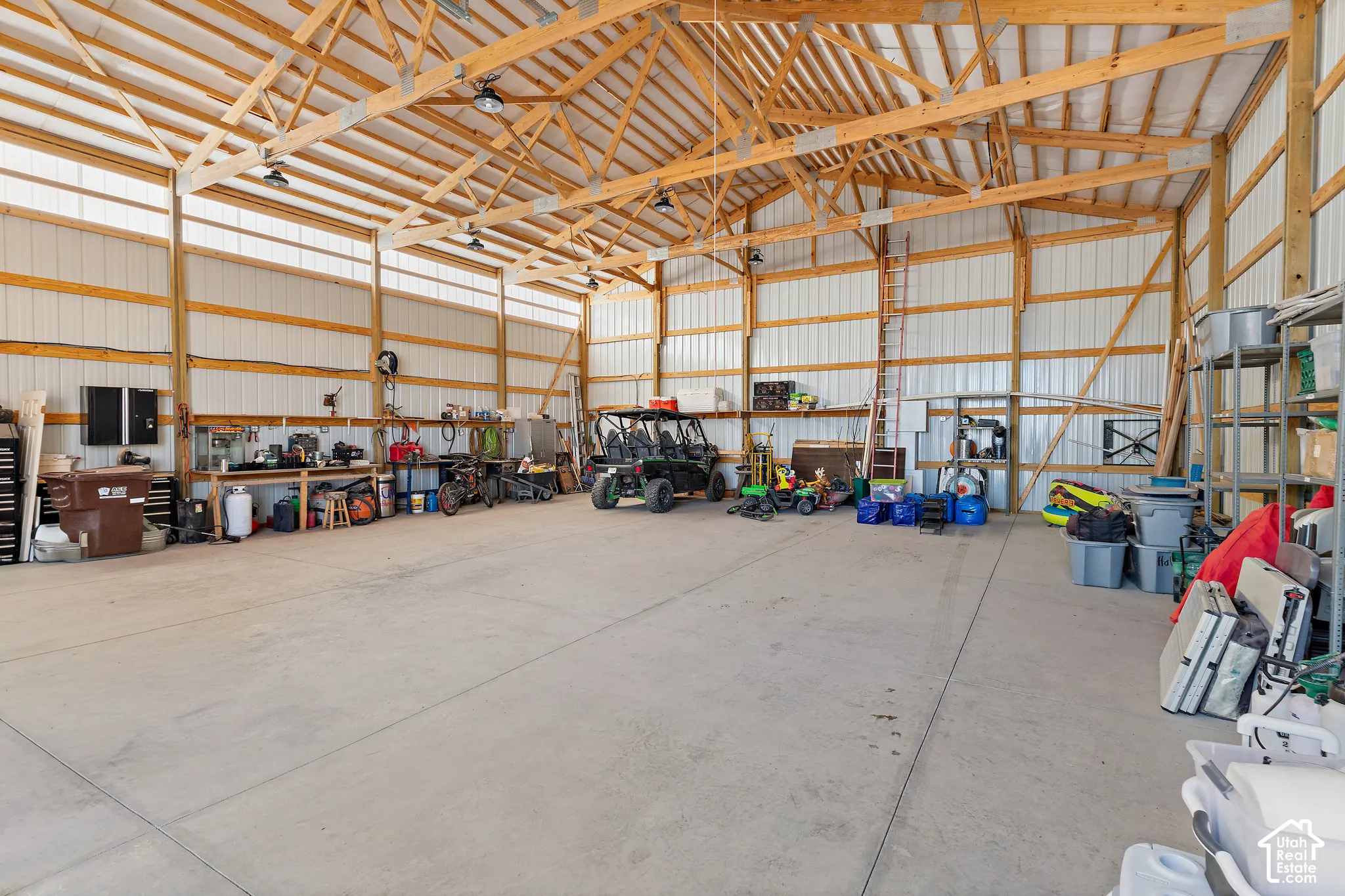 Spacious garage with exposed wood beam ceiling, concrete flooring, and ample lighting fixtures