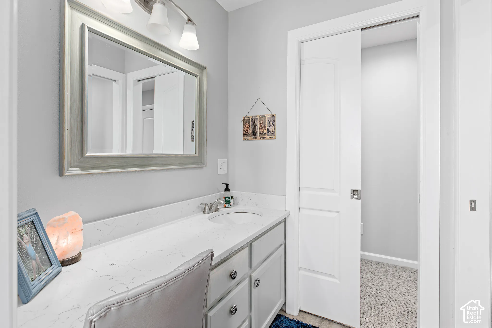 Vanity with a polished silver-framed mirror, contemporary lighting fixture, undermount sink, and a sliding panel door