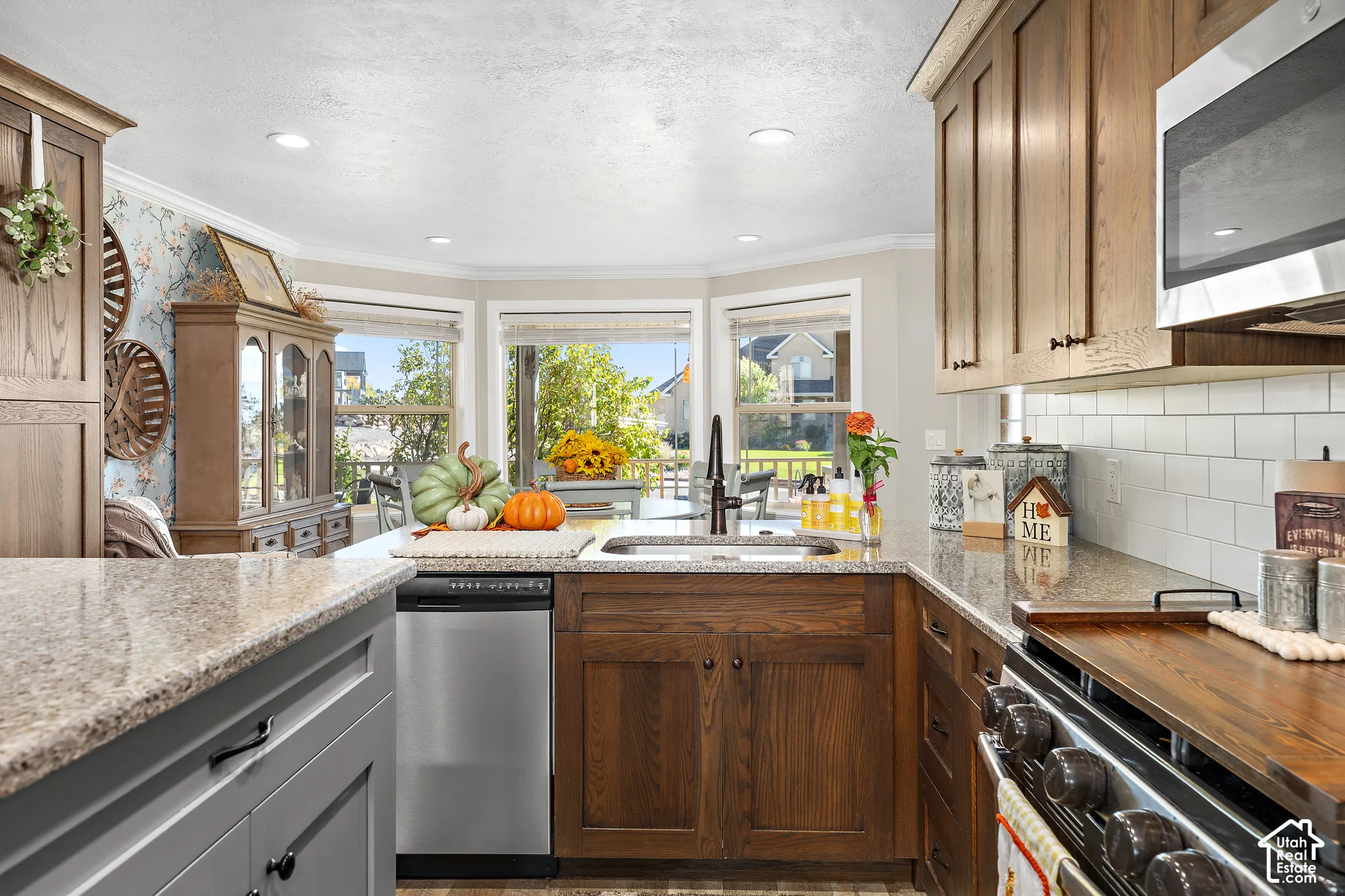 Kitchen featuring wood cabinetry, stainless steel appliances, white subway tile backsplash, and light-toned countertops