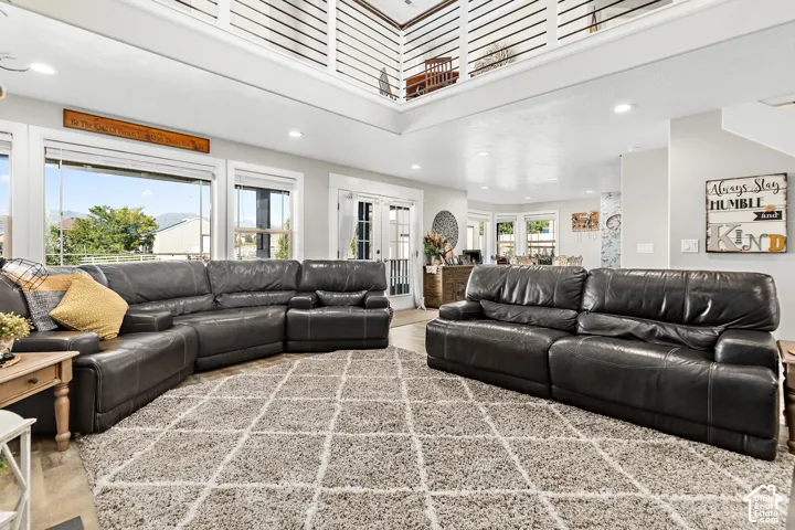 Vaulted ceiling with an open mezzanine, abundant natural light, recessed lighting, and wood-finish flooring