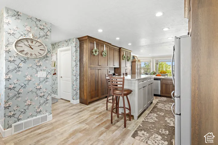 Kitchen featuring wood-finish flooring, recessed lighting, wood cabinetry, a center island with a light-colored countertop, and a window above the sink