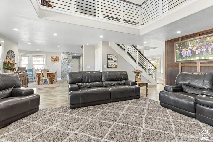 Spacious living area featuring high ceilings, wood-finish flooring, and a modern open-tread staircase with horizontal railings